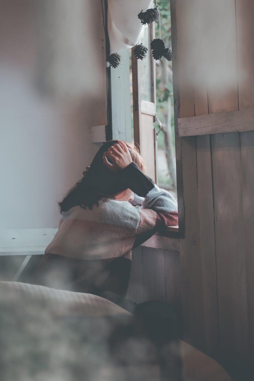 A photo of a woman all by herself staring out the window.